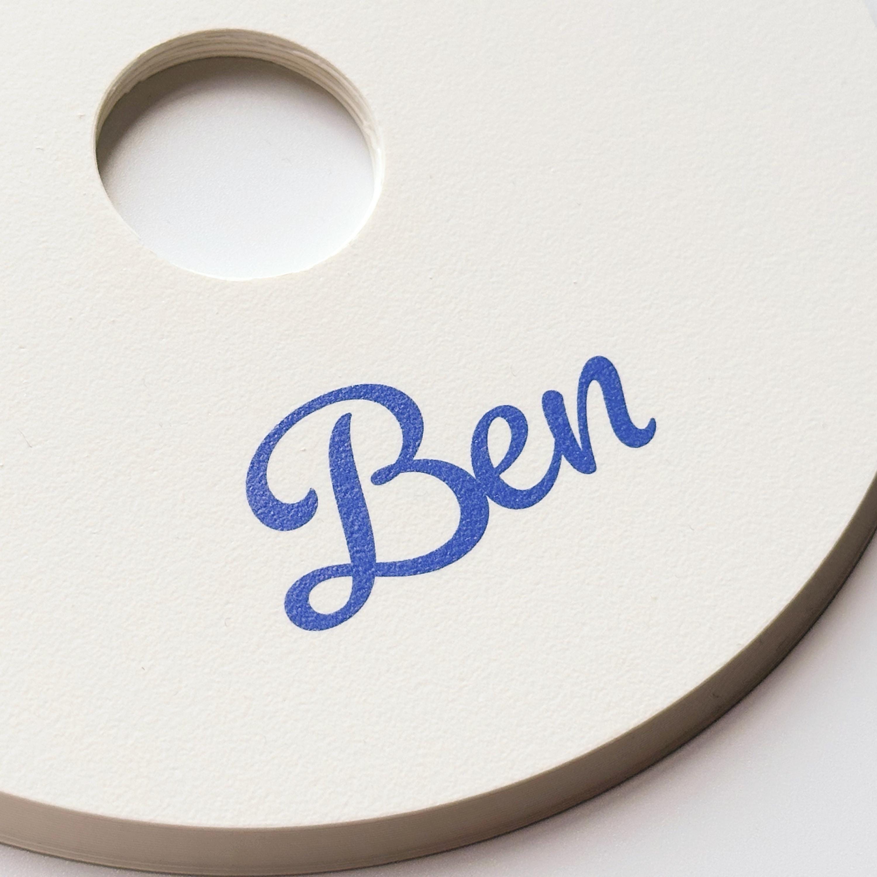 A close-up of the cream-colored round base shows the blue script text "Ben" and the central hole.